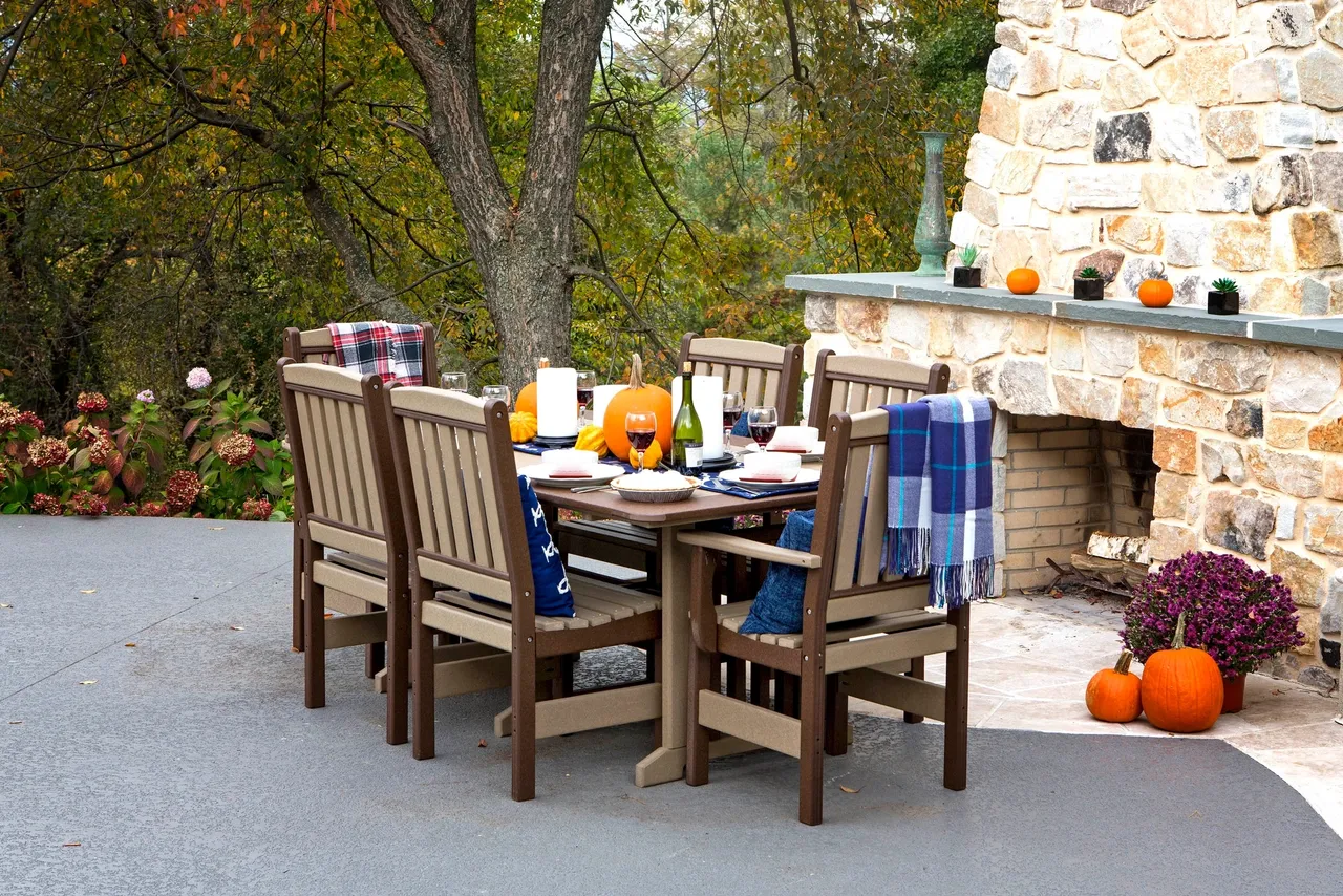 A table and chairs set up outside in front of an outdoor fireplace.