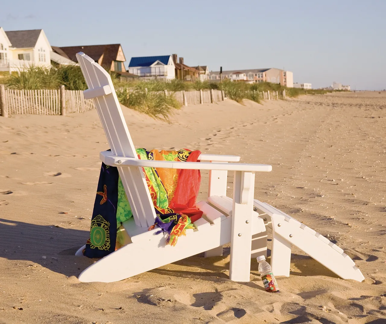 A white chair on the beach with a towel draped over it.