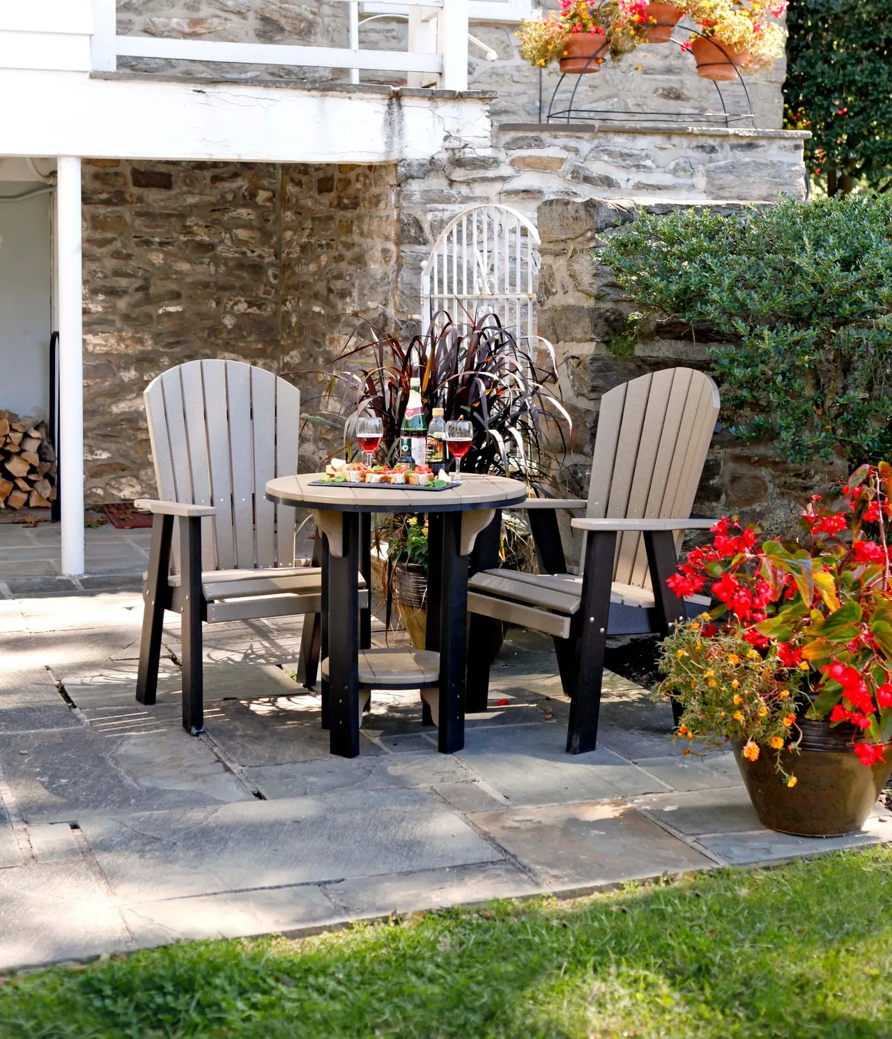 A patio with two chairs and table on the side of the house.