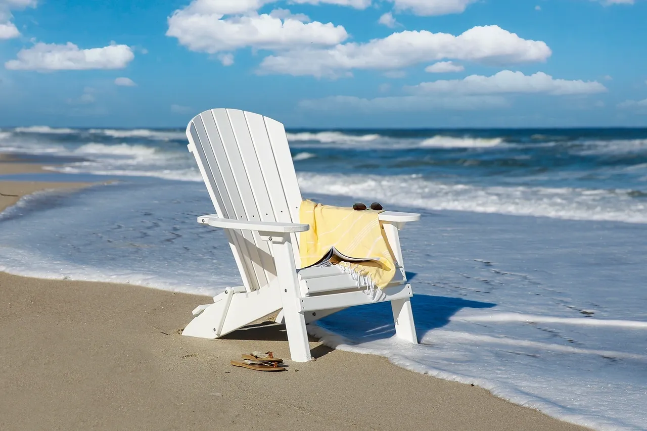 A white chair on the beach near the ocean.