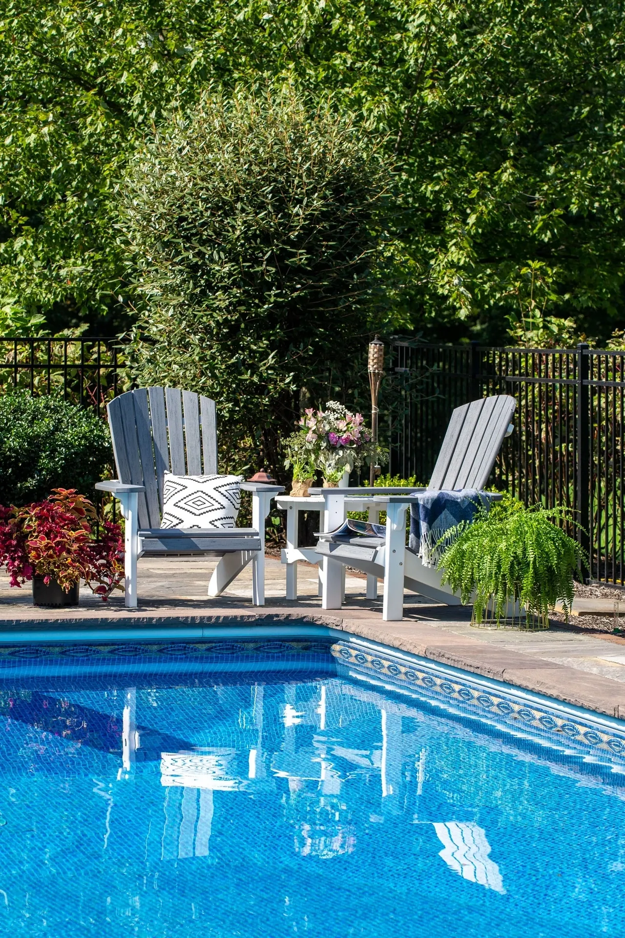 A couple of chairs sitting next to the side of a pool.