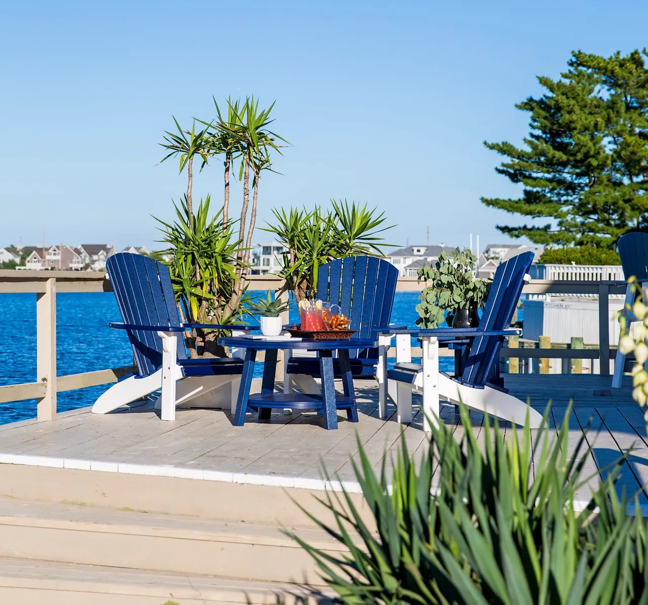 A deck with chairs and table overlooking the water.