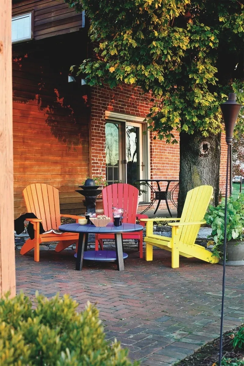 A patio with four colorful chairs and a table.