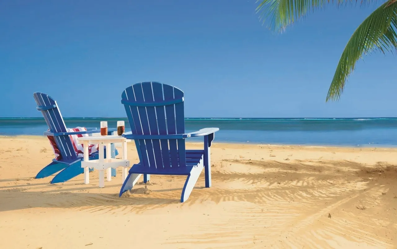 A blue chair on the beach with drinks and an ocean view.